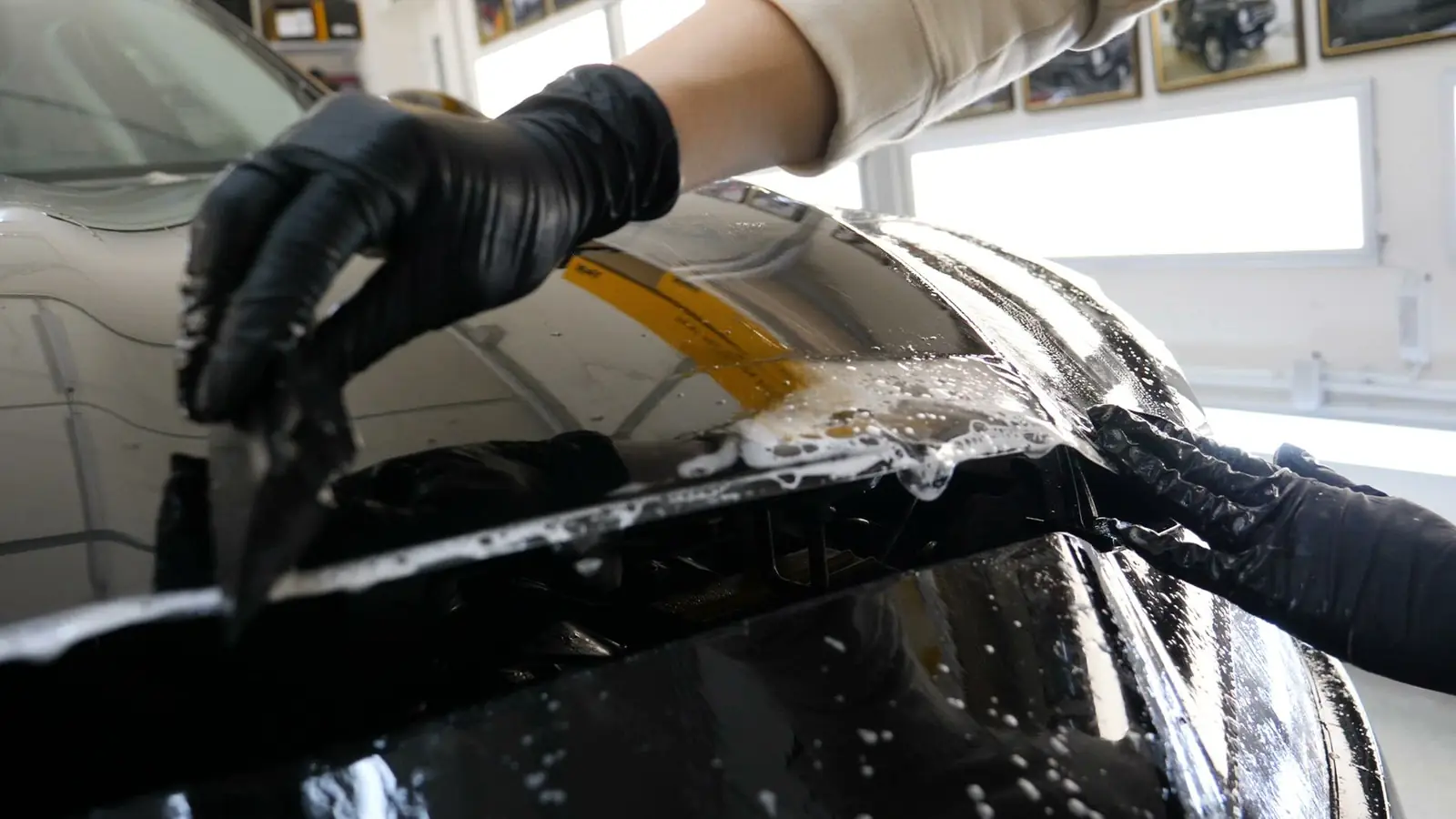 Paint protection film being squeegeed onto a vehicle panel