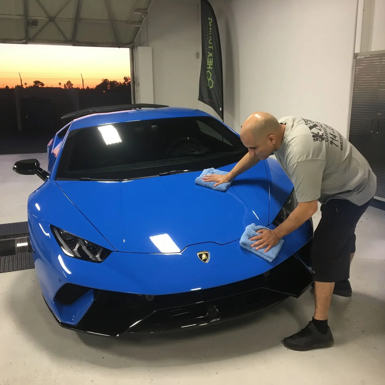 STRATA detailer hand-cleaning a blue Lamborghini Huracán in the shop